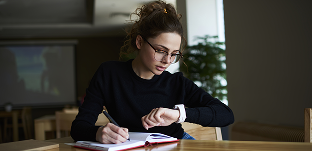 woman writing looking at watch