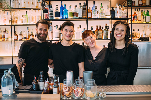 Group of bartenders smiling behind a bar